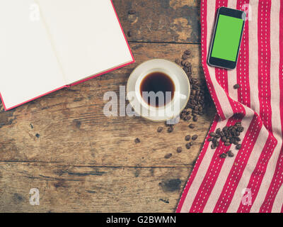 Coup de frais généraux de café concept avec tasse de thé, une serviette, un livre ouvert et un téléphone intelligent avec un écran vert Banque D'Images