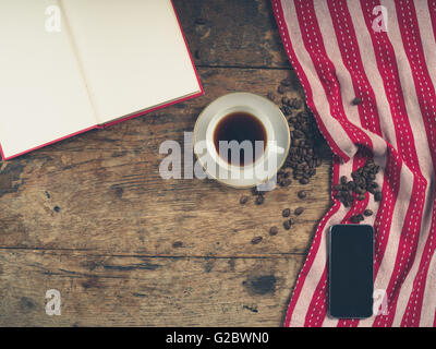 Coup de frais généraux de café concept avec tasse de thé, une serviette, un livre ouvert et un téléphone intelligent Banque D'Images