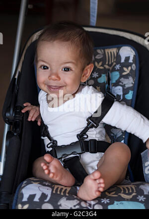 Petit bébé garçon assis dans une poussette à la maison, prêt pour une promenade dans un landau Banque D'Images