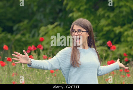 Belle jeune fille jouant dans les champs de coquelicots Banque D'Images