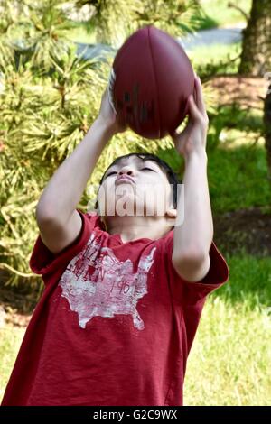 Un jeune garçon jouant au football dans un champ Banque D'Images