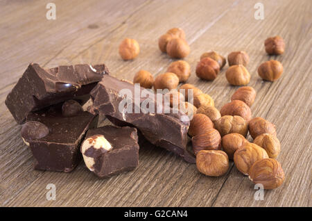 Le chocolat avec des noisettes en morceaux sur une table en bois rustique Banque D'Images