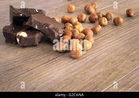 Le chocolat avec des noisettes en morceaux sur une table en bois rustique Banque D'Images