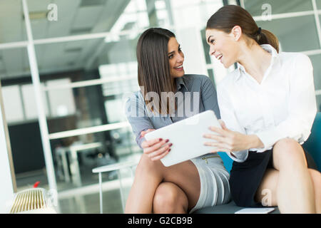 Deux jolies jeunes femmes avec le comprimé dans le bureau moderne Banque D'Images