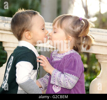 Jeune fille timide et boy kissing tendrement dans le parc Banque D'Images