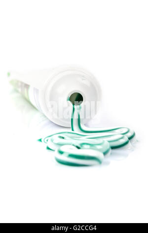 Le tube de pâte dentifrice avec débordement, vert et blanc à rayures, fond blanc, de la réflexion, Banque D'Images