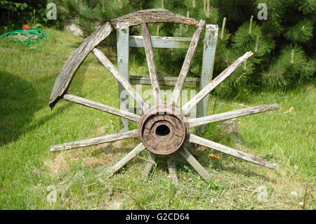 Ancienne roue de chariot en bois dévasté standing in garden Banque D'Images