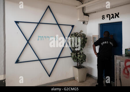 Un gardien du Service pénitentiaire d'Israël communément connu en Israël par son acronyme Shabas ou ISP en anglais parle avec un détenu par une fenêtre de porte de cellule à l'intérieur de la prison d'Eshel près de Beersheba en Israël Banque D'Images
