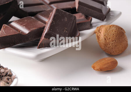 Les portions et les copeaux de chocolat avec amandes close up sur un récipient en porcelaine blanche sur un tableau blanc dans la cuisine. L'horizontale Banque D'Images