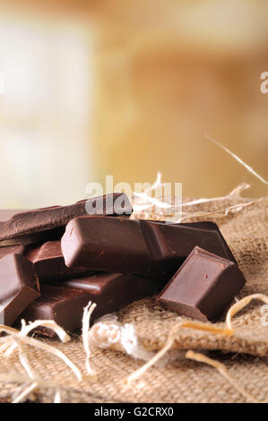 Tas de portions sur de la toile de jute chocolat artisan sac sur une table en bois brun close up. Composition verticale. Vue avant Banque D'Images