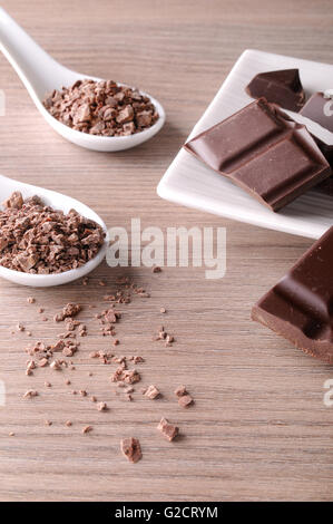 Les portions et les copeaux de chocolat sur un récipient de porcelaine blanche sur une table en bois brun. Composition verticale. Vue supérieure élevée Banque D'Images