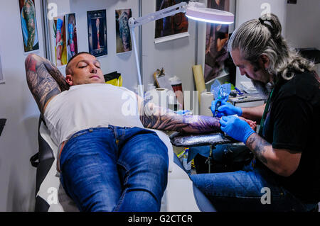 BELFAST, IRLANDE DU NORD. 28 MAI 2016 - 6th Conférence de Tattoo en Irlande du Nord. Un tatouage artiste dessine le tatouage sur le bras d'un client masculin Banque D'Images