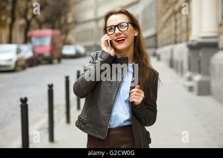 Businesswoman marche dans la rue tout en parlant au téléphone intelligent. Happy smiling caucasian business woman occupé Banque D'Images