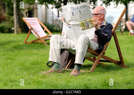 Hay Festival - Vendredi 27 mai 2016 - Un festival le visiteur profite d'une occasion de s'asseoir et lire le journal pendant que le soleil brille sur la deuxième journée de l'Hay Festival. Banque D'Images