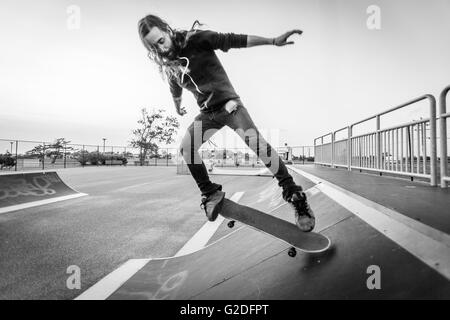 L'homme des jeunes adultes faisant des tours avec Skateboard à Skate Park Banque D'Images