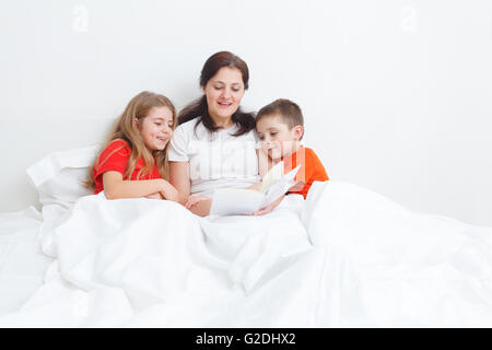 Maman lire un livre au lit pour son enfant avant de dormir Banque D'Images