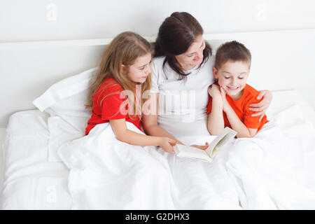 Maman lire un livre au lit pour son enfant avant de dormir Banque D'Images