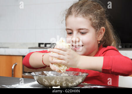 Happy girl le pétrissage de pâte avec les mains dans la cuisine Banque D'Images