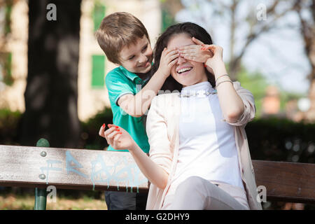 Garçon enfant jouant dans le parc devinez qui avec sa jeune maman ou tante Banque D'Images