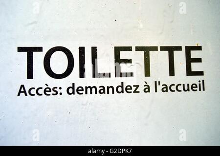 Poster toilettes peint sur une porte de couleur gris avec des sentiers de peinture Banque D'Images