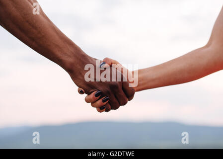 Close-up of young couple holding hands on le Misty Mountain l'arrière-plan. Photo symbolique Banque D'Images