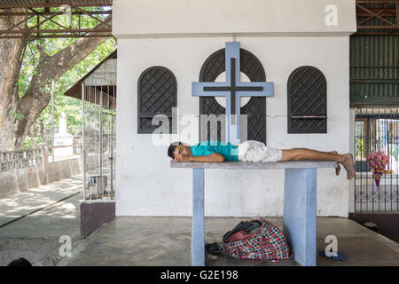 Les personnes vivant dans les cimetières n'est pas rare dans les Philippines.ici un homme dort sur un autel. Banque D'Images