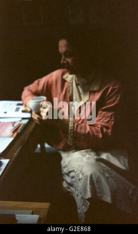 Femme en rose assis au bureau et tenant une chope Banque D'Images