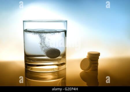 Verre d'eau avec comprimé effervescent et tas de pilules sur la table Banque D'Images