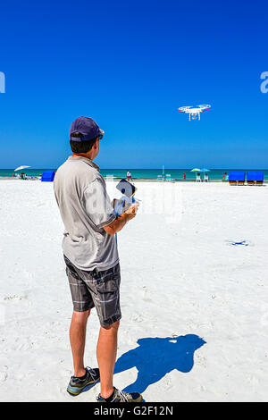 Un pilote de drone manoeuvre l'joy stick sur le contrôleur radio pour un vol de drone non militaires contre un ciel bleu à la plage Banque D'Images