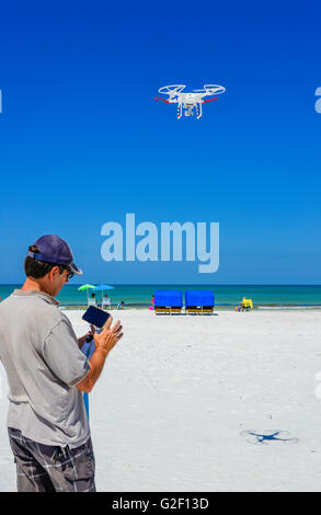 Un pilote de drone manoeuvre l'joy stick sur le contrôleur radio pour un vol de drone non militaires contre un ciel bleu à la plage Banque D'Images