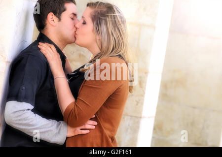 Les amoureux romantique robes noires et brunes s'embrasser dans un parc à l'extérieur des colonnes Banque D'Images