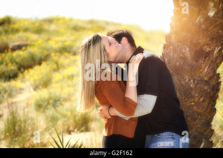 Les amoureux romantique robes noires et brunes s'embrasser dans le domaine sous un plam tree avec sun flare Banque D'Images