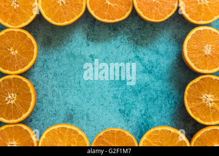 Fnatiral cadre fabriqué avec les moitiés d'oranges sur fond vibrant bleu Banque D'Images