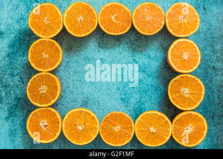 Cadre naturel fait avec des oranges sur les moitiés d'arrière-plan dynamique bleu Banque D'Images