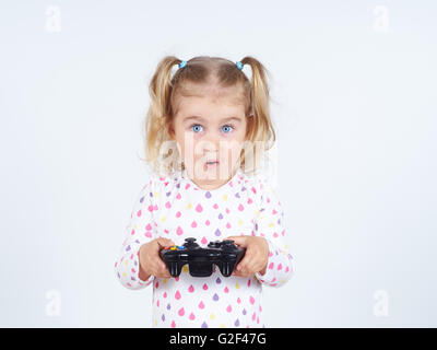 Petite fille à jouer aux jeux vidéo avec manette dans les mains. Banque D'Images