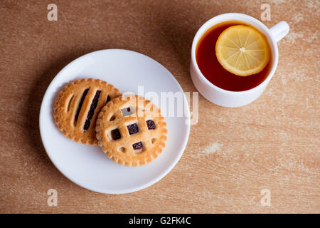 Tasse de thé et de citron, les biscuits avec de la confiture dans une soucoupe sur la table view Banque D'Images