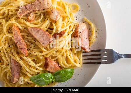 Spaghetti carbonara sur plaque blanche avec une fourchette Banque D'Images