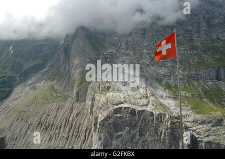 Drapeau suisse en volant sur le vent en haute montagne à proximité de Grindelwald dans les Alpes en Suisse. Banque D'Images