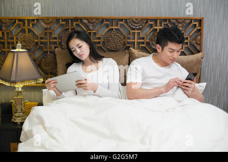 Jeune couple et smart phone in bed Banque D'Images