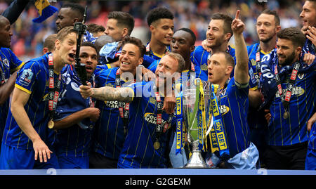 L'AFC Wimbledon's Sean Rigg (centre) et ses coéquipiers célèbrent avec le trophée après son côté gagne le pari du Ciel deux Play-Off ligue match de finale au stade de Wembley, Londres. Banque D'Images