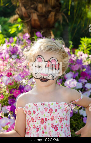 Belle fille blonde avec Bonjour Kitty face painting sur floral background Banque D'Images