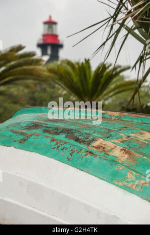 Bateau en bois avec une coque grattée tiré vers le haut au-dessus du littoral sous le phare de Saint Augustine en Floride du Nord. (USA) Banque D'Images