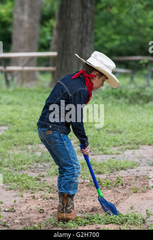 Un jeune garçon en tenue de cow-boy la collecte des grenouilles et des insectes à McKinney Falls State Park, Austin, Texas. USA. Banque D'Images