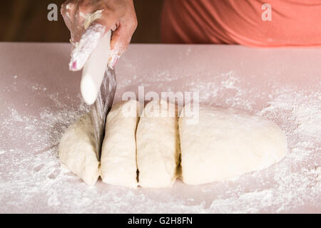 Femme à l'aide d'un coupe-pâte pour diviser la pâte à pain naan en six portions égales qui sont aplatis et cuit au four. Les boulangers et les ap Banque D'Images