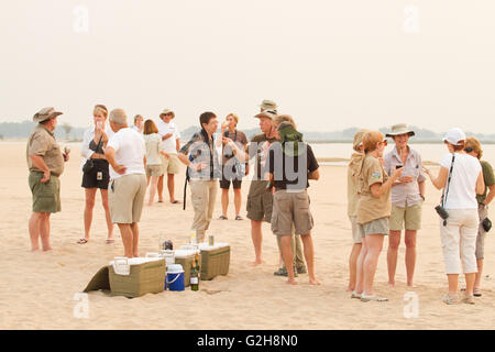 Les personnes bénéficiant d'un safari sundowner fête sur la plage à côté de la rivière Zambèze dans Lower Zambezi National Park, Zambie, Afrique Banque D'Images