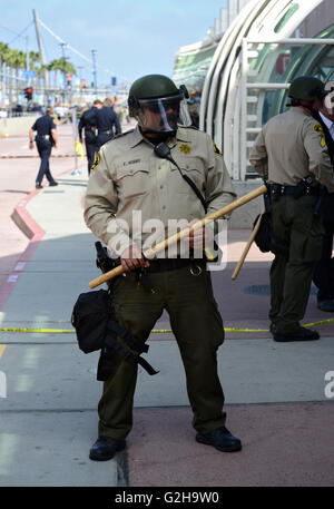 Un officier de police de San Diego est titulaire d'un Billy club tout en habillé en tenue de combat et portant des lunettes de soleil avec un appareil photo intégré à l'extérieur du centre de convention de San Diego après le candidat présidentiel américain Donald Trump a prononcé un discours. / © Craig M. Eisenberg Banque D'Images