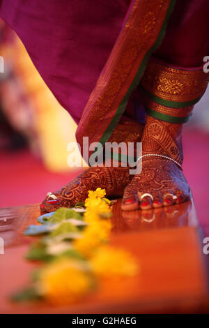 Les pieds de la mariée au cours d'un rituel de mariage traditionnel indien de l'progression plus de fleurs. Banque D'Images
