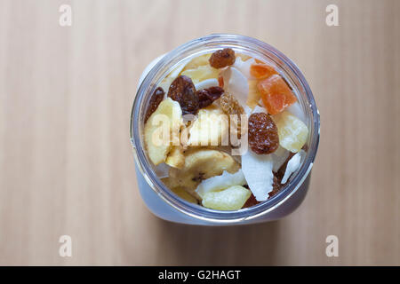 Pot en plastique avec un mélange de fruits secs sur la surface en bois. Focus sélectif. High angle view Banque D'Images