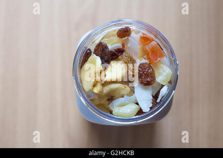 Pot en plastique avec un mélange de fruits secs sur la surface en bois. Focus sélectif. High angle view Banque D'Images