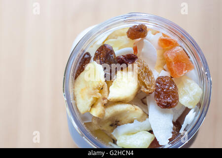 Pot en plastique avec un mélange de fruits secs sur la surface en bois. Focus sélectif. High angle view Banque D'Images